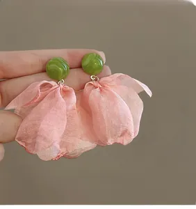 Detail of floral earrings featuring green marble studs and pink mesh fabric petals