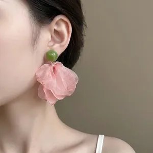 Elegant oversized chiffon floral drop earrings with green bead accent on model