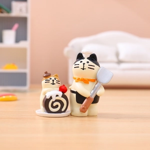 Close-up of chef cat resin figurine and miniature chocolate cake dessert on a desktop