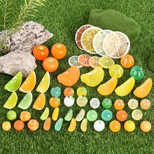Miniature resin fruit slices and citrus ornaments on green grass for DIY crafts
