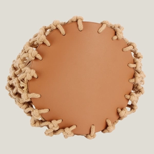 Bottom view of a handmade woven beach bag featuring a brown leather base and rope stitching