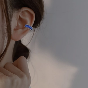 Silver ear cuff with five emerald-cut dark blue zircons worn on the upper ear cartilage