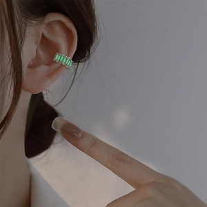 Close-up of ear cuff with five rectangular green zircons worn on the ear cartilage