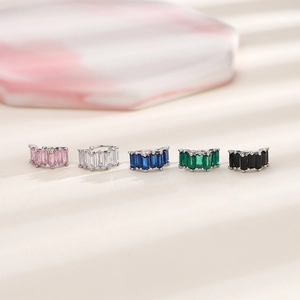 Macro shot of baguette-cut zircon ear cuffs in five colors on a marble stone base