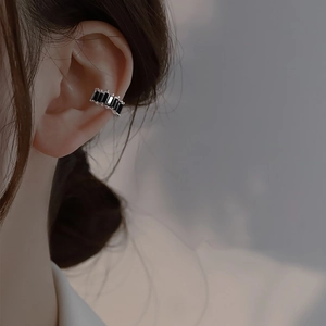 Close-up of black square zircon ear cuff with five faceted stones on a silver metal base