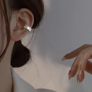 Close-up of a silver ear cuff featuring rectangular baguette-cut cubic zirconia crystals