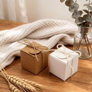 Detail of square kraft paper gift boxes with rustic twine bows and eucalyptus decor