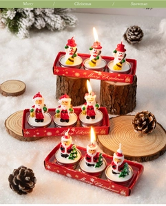 Close-up of Santa and Snowman Christmas candles in red gift boxes on wooden stand