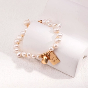 Elegante bracciale di perle con ciondolo a cuore e medaglietta Good Luck su espositore