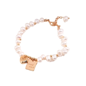 Bracciale di lusso in perle d'acqua dolce con ciondoli a cuore oro e Good Luck su bianco