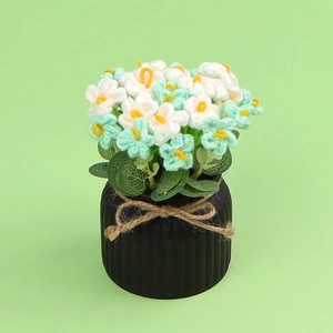 Detail of hand-knitted crochet flowers in green and white with a black ribbed ceramic pot
