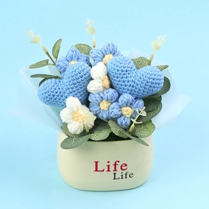 Macro view of blue knitted heart flowers in white ceramic pot with clear yarn textures