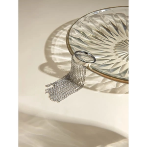 Detailed view of silver tassel chain ring on a glass edge with artistic shadow effects