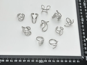 Flat lay macro of geometric silver rings and earrings on a white measurement grid