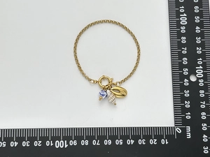 Detail of a gold chain bracelet with ceramic bead and shell pendants on a measurement scale