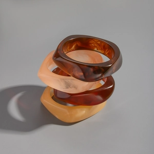 Bracciali geometrici in resina impilati in tonalità ambra, tartaruga e crema