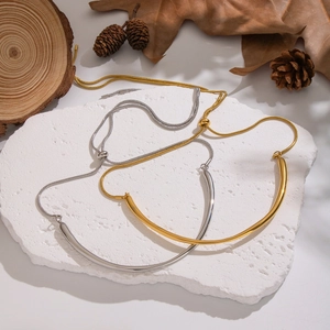 Détail de colliers minimalistes à barre incurvée en or et argent avec chaîne serpent