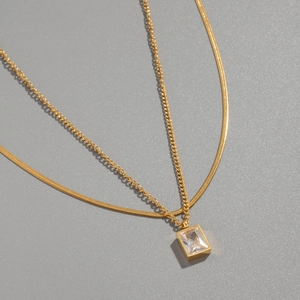Gros plan d'un collier double couche plaqué or 18K avec pendentif zircon carré