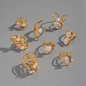 Flat lay macro of eight irregular gold-plated rings set with clear cubic zirconia stones