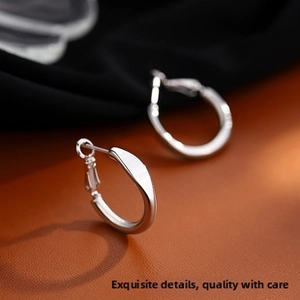 Macro view of minimalist silver twisted hoop earrings with a mirror-finish texture