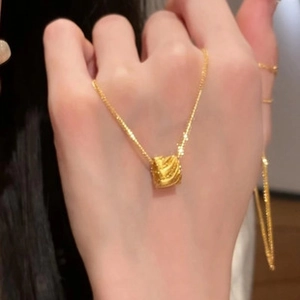 Close-up of golden tulip necklace with a textured square flower pendant on hand