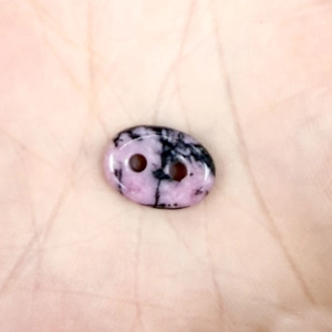 Macro detail of oval pink rhodonite stone bead with double holes for DIY jewelry