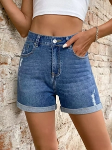 Women's high waist denim shorts with embossed pattern and rolled cuffs on brick wall background