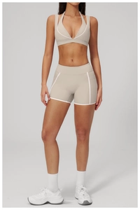 Detail of beige yoga set showing white piping design and minimalist fitness aesthetic