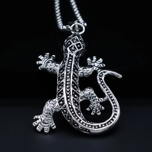 Macro shot of silver lizard pendant with intricate scale textures on a black background