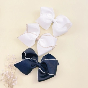 Detailed view of three handmade grosgrain ribbon hair clips with wavy edge stitching