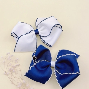Macro shot of two handmade grosgrain bow hair clips with contrast scalloped edges for girls