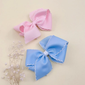 Close-up of handmade grosgrain ribbon hair clips with delicate white scalloped lace edges
