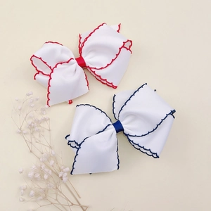 Detail of grooved ribbon hair clips with wavy stitching in red and navy blue