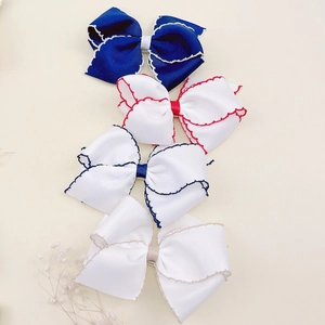 Detailed view of four grosgrain ribbon hair clips with wavy stitching in navy and white
