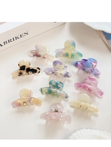 Flat lay of 10 tortoiseshell and marble acetate hair claws on a minimalist surface