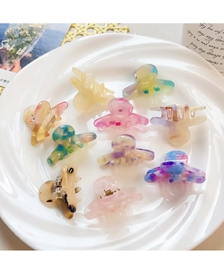 Detailed top view of colorful butterfly acetate hair clips with marble patterns in a ceramic dish