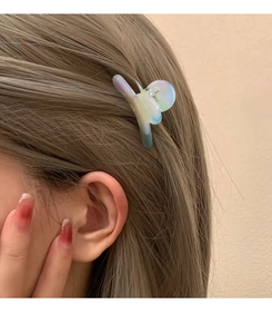 Detail of a translucent gradient acetate hair claw clip worn on a woman's side hair