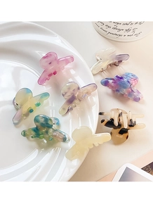 Assortment of colorful acetate hair claws in pastel and marble patterns on a white plate