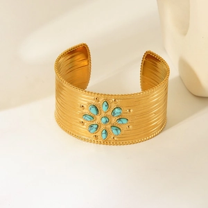 Detail of 18K gold-plated cuff featuring turquoise stone flower and brushed metal texture