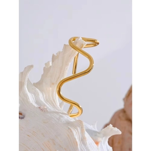 Minimalist gold wavy open bangle bracelet elegantly displayed on a white seashell