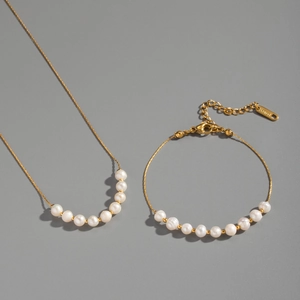 Détail de la parure collier et bracelet en perles d'acier doré avec poinçon S.Steel