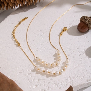 Détail d'un collier de perles d'eau douce naturelles avec perles dorées 18K sur pierre blanche