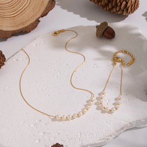 Détail de parure collier et bracelet en perles d'eau douce sur pierre avec finition or 18K