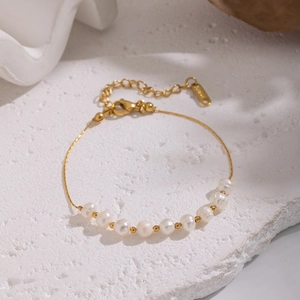 Vue détaillée d'un bracelet en perles naturelles avec chaîne fine plaquée or 18 carats
