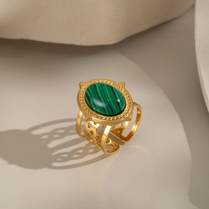 Macro detail of gold-plated stainless steel ring featuring oval green stone and woven band