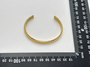 Vista dall'alto dettagliata di un bracciale rigido dorato con trama a intreccio e diametro 60 mm