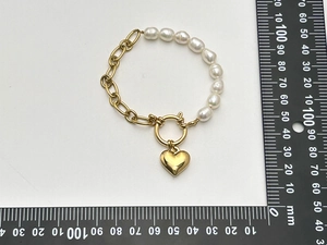 Detail eines Perlenarmbandes mit Herzanhänger und Maßangaben auf dem Lineal