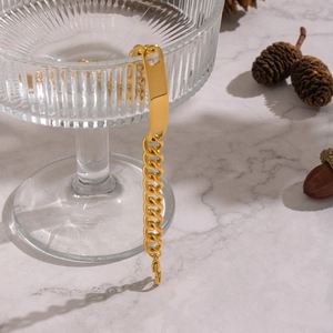 Gros plan d'un bracelet gourmette doré avec plaque d'identité sur décor en marbre