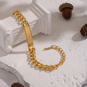 Vue détaillée d'un bracelet gourmette doré avec plaque d'identité sur pilier