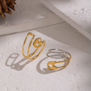 Detailed view of geometric safety pin rings in gold and two-tone silver finishes